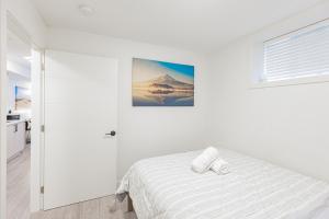 a white bedroom with a bed and a picture on the wall at Dumfries Guest Room in Vancouver in Vancouver