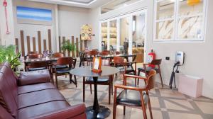 a restaurant with couches and tables and chairs at Hotel WITH OK in Jakarta