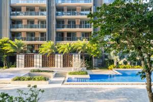 an apartment building with a swimming pool and trees at 三亚海棠湾蔚蓝海湾公寓 in Sanya