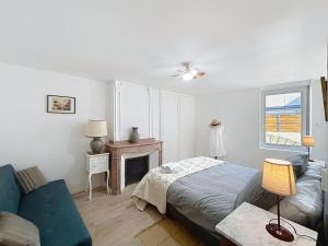 a bedroom with a bed and a couch and a fireplace at Le Lies - Appartement proche de la mer in Salles-d'Aude
