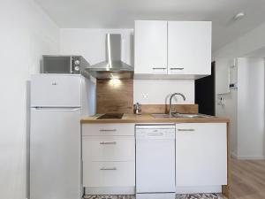 a white kitchen with a sink and a refrigerator at Le Lies - Appartement proche de la mer in Salles-d'Aude