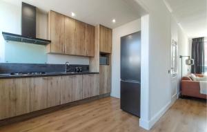 a kitchen with wooden cabinets and a black refrigerator at 3 Bedroom Nice Home In Oost-Souburg in Oost-Souburg +17 photos