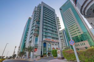 um edifício alto numa cidade com palmeiras em Hawthorn Extended Stay by Wyndham Abu Dhabi City Center em Abu Dhabi