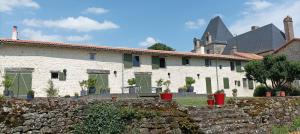 a large white house with a stone wall at Escale Gâtine in La Chapelle-Bertrand