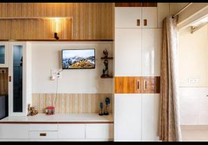 a kitchen with white cabinets and a tv on the wall at cozy place-paramount golf forest in Greater Noida