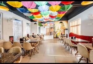 a restaurant with tables and chairs and a ceiling with colorful umbrellas at cozy place-paramount golf forest in Greater Noida