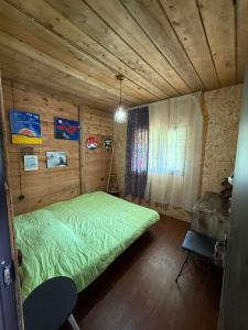 une chambre avec un lit vert dans une pièce en bois dans l'établissement Welcome to Tamara Cottage, à Tba
