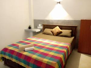 a bedroom with a bed with a colorful blanket at Yeli gray house in Weligama