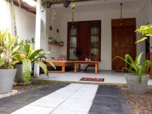 a front porch of a house with a wooden bench at Yeli gray house in Weligama