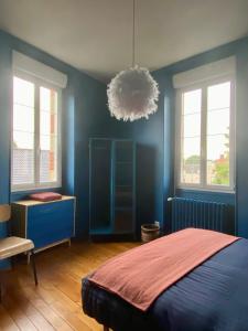 a bedroom with blue walls and a bed and a chandelier at Les LOTUS de BELLE-YLE in Yvré-lʼÉvêque