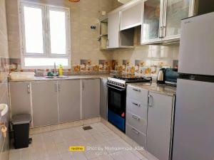 Ţaymissahにあるاستراحة الاصالة alasalahの白いキャビネットとコンロ付きオーブンを備えたキッチン