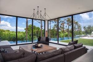 a living room with a couch and a table at Luxury 5BR Canggu Villa with Private Pool, Rice Fields View & Beach Nearby - The Palm House in Canggu