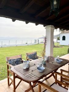 a wooden table on a patio with a view of the ocean at Beachfront Villa with Garden - Valentine Corfu in Mesongi