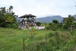 a house in the middle of a field with a fence at Brownstones Resort in Kanthalloor