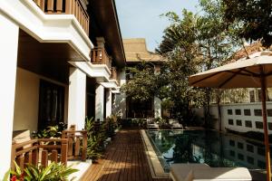 an external view of a house with a swimming pool and an umbrella at Athena Hotel in Pakse