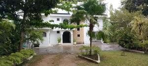 a white house with a courtyard with palm trees at Imani holiday homes in Mtwapa