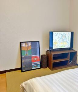 Un dormitorio con una cama y un televisor sobre un mueble. en 交通便利 叠寝室1-4人一線直通 池袋 新宿 涉谷 原宿 惠比寿近い, en Tokio