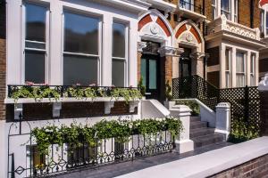 een huis met een wit hek met planten erop bij NOX Kensington in Londen