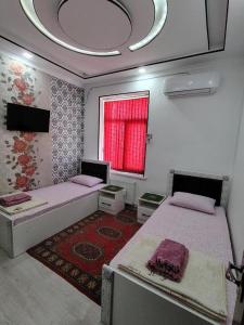 una habitación con dos camas y una ventana en KAMIR Guest House, en Bukhara