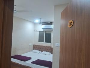 a small bed in a small room with a wooden door at Hotel Ruby in Ujjain