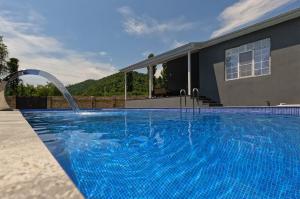 a swimming pool with a fountain in front of a house at White Gray House Gabala Vandam in Gabala