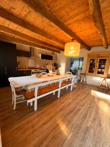 una cucina con un tavolo da pranzo bianco con panche di Ti ar Goanag, Maison de vacances, Séjour, Week-end a Pleyben