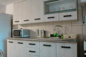 Una cocina con gabinetes blancos, un fregadero y un microondas. en Casa Gabi, en Turda 33 fotos más