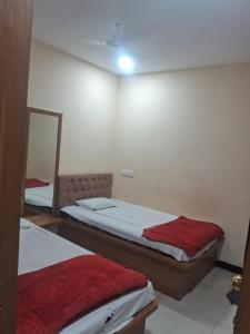 a bedroom with two beds and a mirror at Hotel Ruby in Ujjain +1 photo
