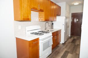une cuisine avec des armoires en bois et un four blanc dans l'établissement Emerald Room at Brighton Beach 2Min Walk to Ocean n Subway Chic Stay, à Brooklyn