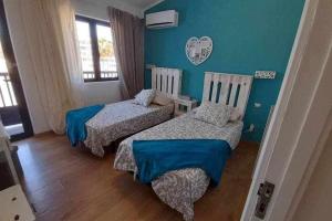Dos camas en una habitación con paredes azules. en Vistas de Ensueño al Mar en Playa del Águila, en Playa del Águila 17 fotos más