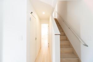 a white hallway with stairs in a house at Miraie Suzuka Shimomida in Suzuka