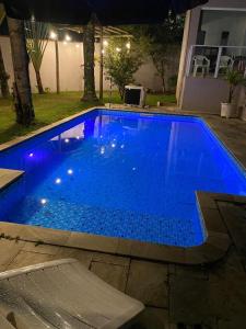 a blue swimming pool with lights in a yard at night at Casa com Piscina, Churrasqueira e Quartos amplos in São Bernardo do Campo