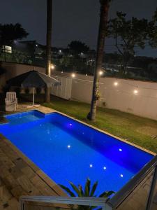 a blue swimming pool in a backyard at night at Casa com Piscina, Churrasqueira e Quartos amplos in São Bernardo do Campo