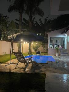 a chair and an umbrella next to a pool at night at Casa com Piscina, Churrasqueira e Quartos amplos in São Bernardo do Campo