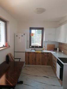 eine Küche mit Holzschränken und einem weißen Kühlschrank in der Unterkunft Pelister Riverside Villa in Bitola