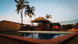 a swimming pool with a gazebo and palm trees at Royal Motel Rockhampton in Rockhampton