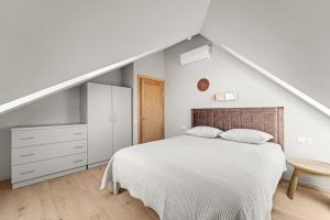 a white bedroom with a bed and a staircase at Dunique in Palanga