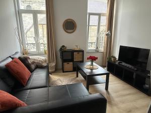 a living room with a black couch and a tv at Petit appartement central Chimay in Chimay