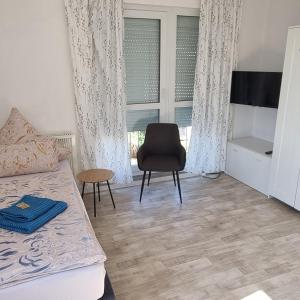 a bedroom with a bed and a chair and a window at Ferienwohnung zur Schmiede in Prödel