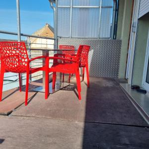 two red chairs and a table on a balcony at Ferienwohnung zur Schmiede in Prödel