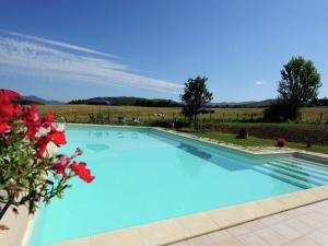 a large blue swimming pool with red flowers at Stunning Farmhouse in Passignano with Pool in Passignano sul Trasimeno