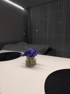 a small glass vase with purple flowers on a table at Аркадия ! ЖК Атмосфера ,панорама моря ,паркинг in Odesa