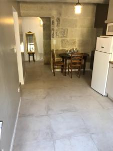 a kitchen and dining room with a table and a refrigerator at La maison de jeanne in Vauvert
