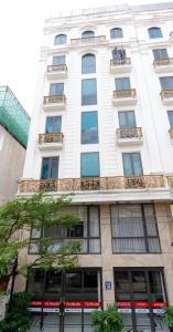 a tall white building with windows on a street at TQ Helios Hotel & Apartment in An Khê