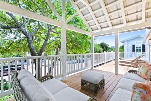 a screened porch with white furniture on a wooden deck at Sugar in Santa Rosa Beach