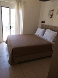 a bedroom with a large bed with a large window at Ifigeneia Infinity Suites in Néa Alikarnassós