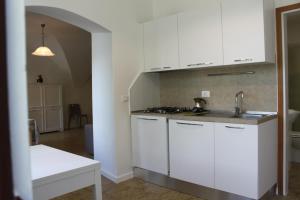 a kitchen with white cabinets and a sink at Studio Zu - Lakeside Apartment in Riva di Solto