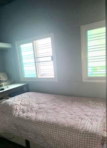 a bedroom with a bed and two windows at Uncle Ong Home's Khaokho บ้านพักลุงโอ่งโฮม เขาค้อ in Khao Kho