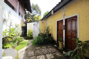 a yellow house with a wooden door and a walkway at Taman Ayu Homestay Munduk Mitra RedDoorz in Munduk