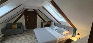 a attic bedroom with a bed and a chair at Syrenka Apartamenty in Ustka